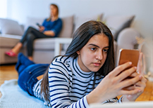 Teen using cell phone while parent looks on