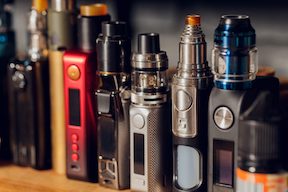 Vaping devices lined up in a row all in different colors and sizes.
